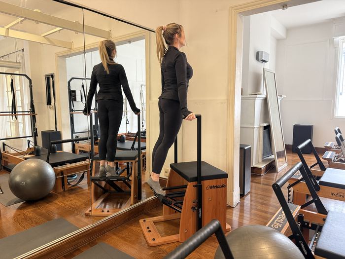 Alumna trabajando de pie frente al espejo del Estudio Uno Pilates