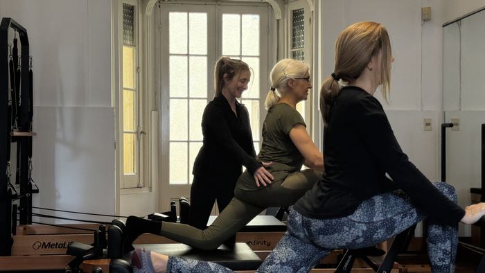 Corrección de postura durante una clase de Pilates en grupo reducido