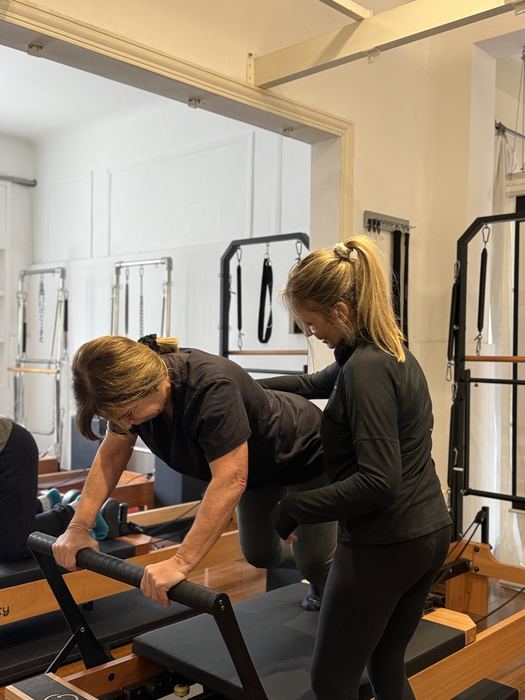 Dos instructoras acompañando a una alumna durante su clase de Pilates